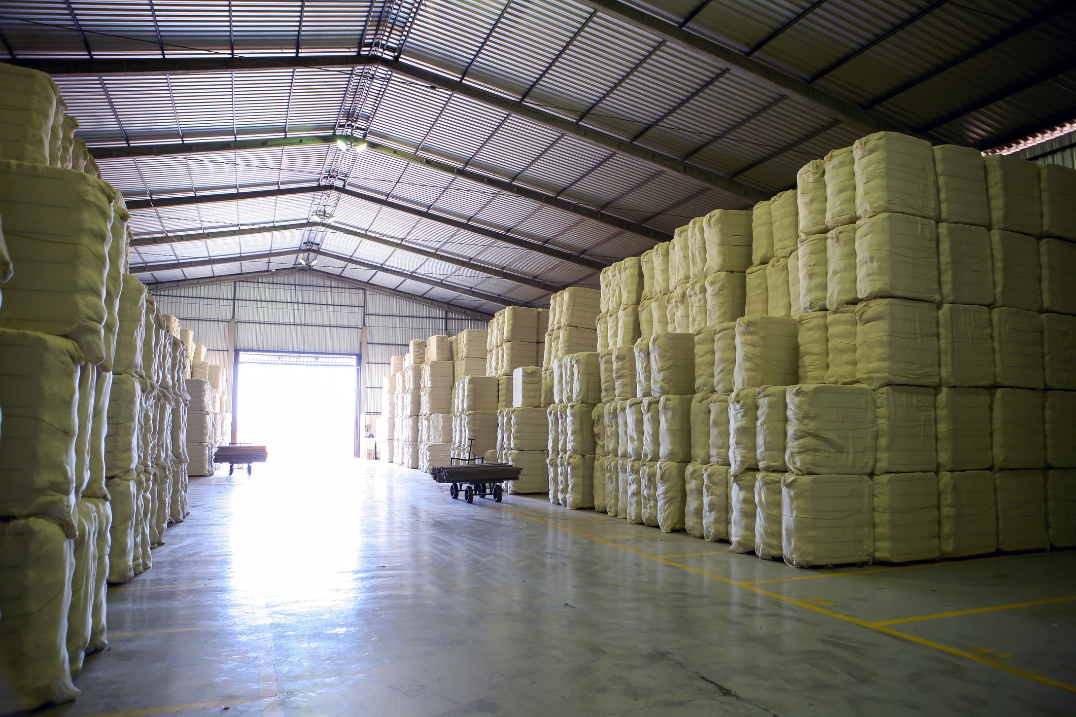 The inside of a large storage facility with hundreds of stacked bales of hemp fiber.