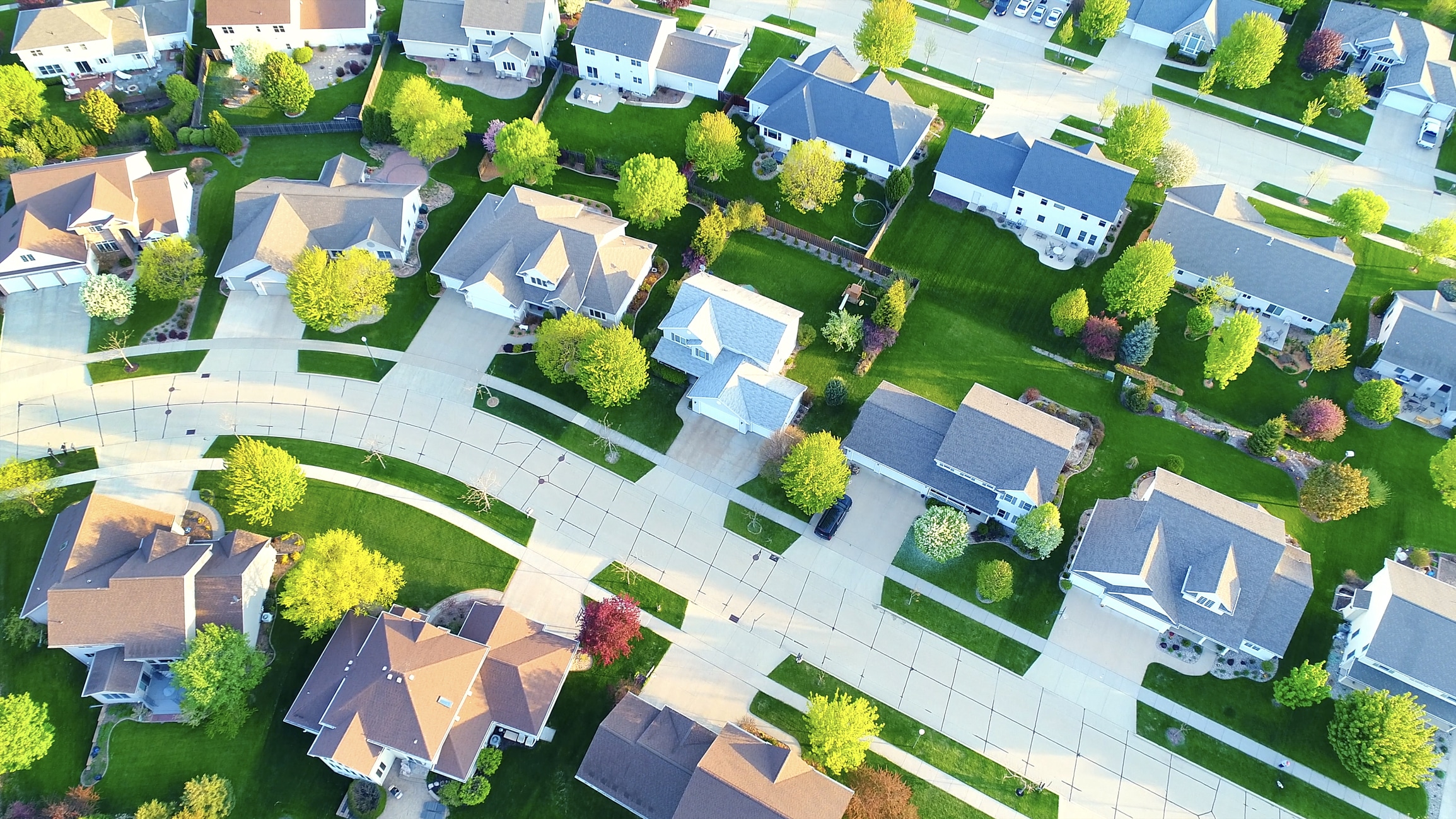 Aerial view of a residential neighborhood of homes and streets at sunrise.