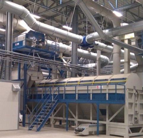 Interior of an industrial plant with machinery, steel pipelines, and stairs.